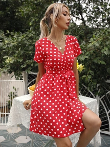 Détail d'une robe courte rouge à pois avec décolleté en V et ceinture nouée à la taille