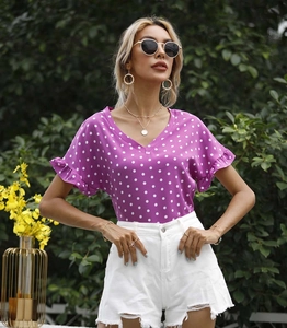 Detail von violettem Polka-Dot-Oberteil mit V-Ausschnitt und weißen Denim-Shorts