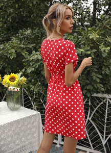Détails d'une robe d'été rouge à pois avec taille ajustée et manches courtes