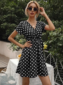 Détail du col en V et de la ceinture sur une robe d'été noire à pois pour femme