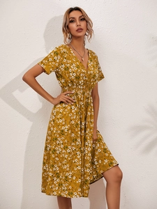 Detail of smocked elastic waist and delicate floral print on mustard yellow dress