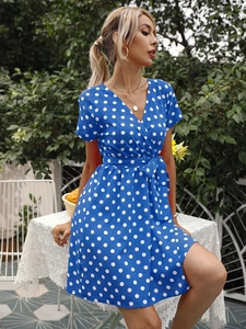 Détail d'une robe bleue à pois avec col en V croisé et ceinture ajustable à la taille