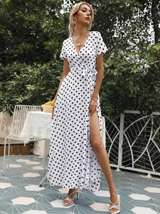 Detail eines weißen Polka-Dot-Wickelkleides mit V-Ausschnitt und hohem Seitenschlitz