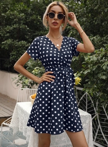 Détail d'une robe à pois bleu marine avec col en V et manches courtes à nouer