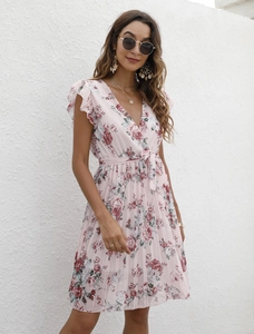 Détail de robe d'été rose fleurie avec col en V, manches volantées et ceinture à la taille
