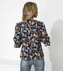 Dettaglio di una camicia a fiori da donna con eleganti volant e maniche lunghe