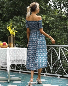 Detailed back view of a navy blue floral off-shoulder smocked dress in an outdoor garden