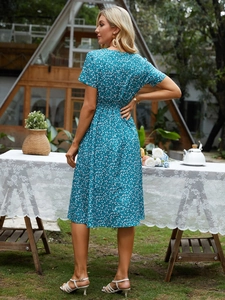 Outdoor back view of a light blue floral short sleeve midi dress with elastic waist
