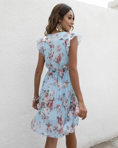 Détail d'une robe fleurie bleu clair montrant l'épaule à volants et l'ourlet plissé