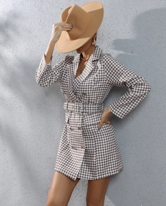 Detail of houndstooth blazer dress featuring double-breasted buttons and matching waist belt