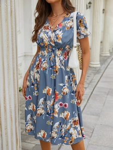 Detail of greyish-blue floral dress featuring a V-neckline and elastic high waist