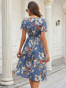 Back view of a blue floral summer dress with elastic waist against a stone column backdrop