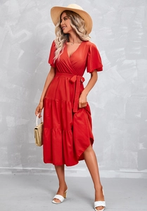 Detail of red V-neck wrap dress with tiered ruffle skirt and waist tie for summer elegance