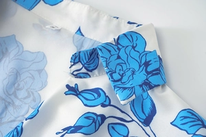 Détail de chemise à fleurs bleues avec étiquette taille S sur tissu blanc