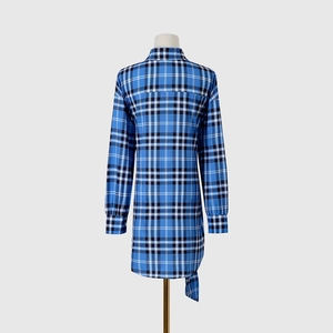 Vista trasera de un vestido camisero a cuadros azules de manga larga con dobladillo irregular