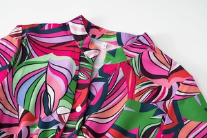 Détail de l'encolure d'une robe à imprimé feuilles tropicales avec bouton blanc