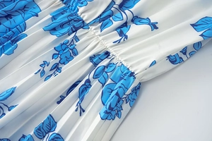 Détail du tissu plissé blanc avec imprimé floral bleu et coutures froncées raffinées