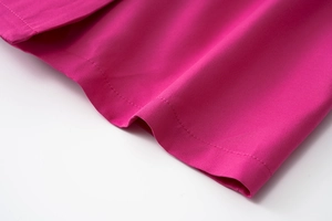 Detailed macro view of double-stitched hem on a vibrant rose pink chiffon dress