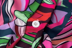 Détail d'un bouton blanc sur le tissu à imprimé floral vibrant d'une robe