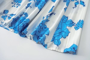 Détail macro du tissu plissé blanc avec imprimé floral de roses bleues et couture d'ourlet