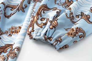 Close-up of elastic cuffs on light blue floral romper with baroque pattern detail