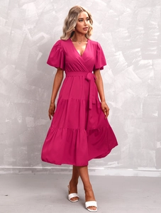 Detailed view of fuchsia V-neck dress with puff sleeves and layered cake skirt texture