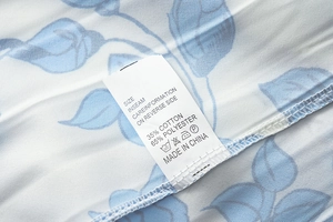 Étiquette d'entretien sur robe fleurie indiquant 35% coton et 65% polyester mélangés