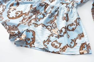 Close-up of baroque floral print and elastic waist detail on light blue romper fabric