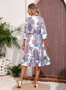 Back view of bohemian paisley print dress with tiered skirt and tie-waist in a garden