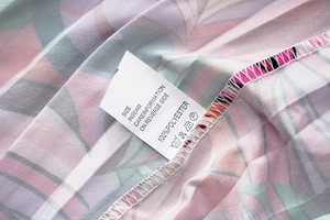 Détail d'une robe à imprimé tropical avec étiquette d'entretien en 100% polyester