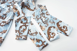 Detailed view of floral baroque print on light blue fabric with waist tie strap detail
