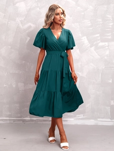 Detail of dark green V-neck dress featuring puff sleeves and tiered ruffle skirt