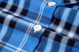 Detalle de tela a cuadros azul y negro con botones redondos blancos y costuras finas