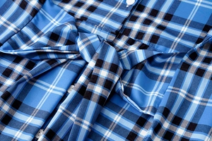 Detalle de la cintura del vestido a cuadros azules con cinturón de lazo y botones blancos