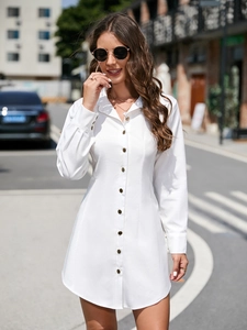 Close-up detail of white long-sleeve shirt dress with contrast metal buttons and lapel