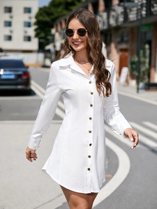 Detail of white long-sleeve shirt dress with gold buttons and waist-defining cut