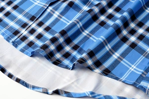 Detalle macro de vestido a cuadros azules que muestra textura de tela y costuras finas