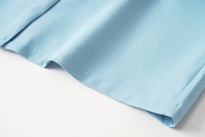 Vue détaillée de la texture du tissu bleu clair du blazer et coutures de l'ourlet