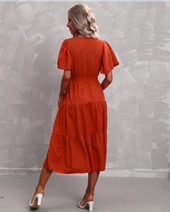 Detail view of tiered skirt hem and high waist design on orange summer dress