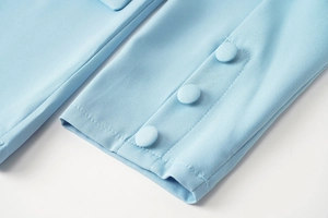 Détail du poignet d'un blazer bleu clair avec trois boutons recouverts de tissu assortis