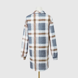 Detail view of women's long plaid coat featuring blue check patterns and curved hemline