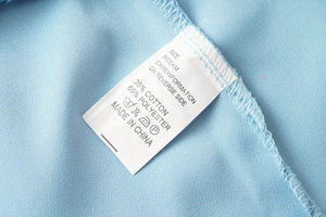 Détail des coutures intérieures et de l'étiquette d'entretien sur un blazer bleu clair
