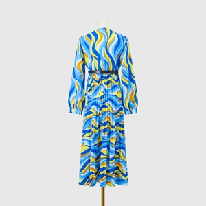 Detail of colorful pleated maxi dress featuring vibrant wave print and black waist belt