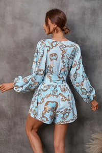 Rear view of a floral baroque print romper featuring long sleeves and cinched waist design