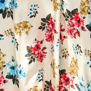 Vue détaillée du tissu imprimé floral avec roses rouges et fleurs bleues sur fond ivoire