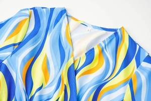 Close-up of V-neckline on long sleeve dress with blue and yellow abstract wave print
