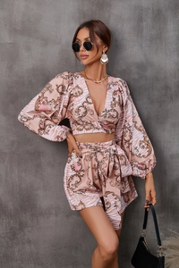 Close-up of pink V-neck wrap top and high-waisted shorts with gold baroque flower print