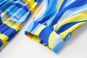 Detailed macro view of pleated fabric with colorful abstract print and cuffed sleeve