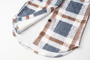 Detail view of plaid flannel coat featuring curved hem and black button accents