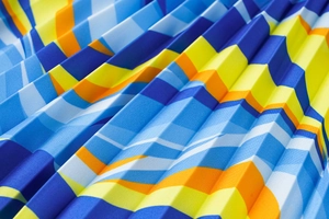 Macro detail of pleated V-neck dress fabric featuring colorful geometric stripe patterns